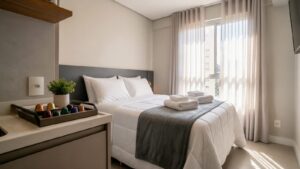 Studio pronto para receber hóspede, com cama arrumada e kit de boas-vindas